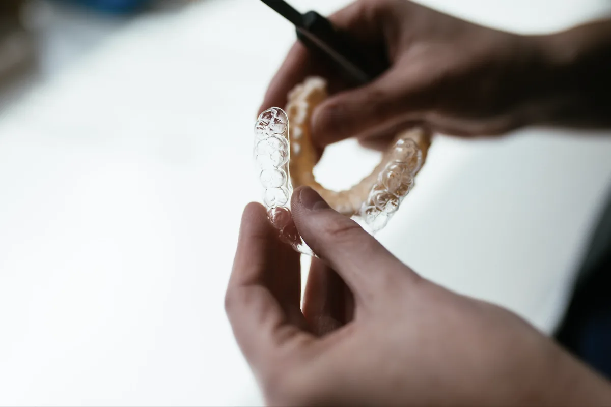 Clear retainer being trimmed from a 3D-printed model of a patient's teeth in the Sturgill Orthodontics in-house lab