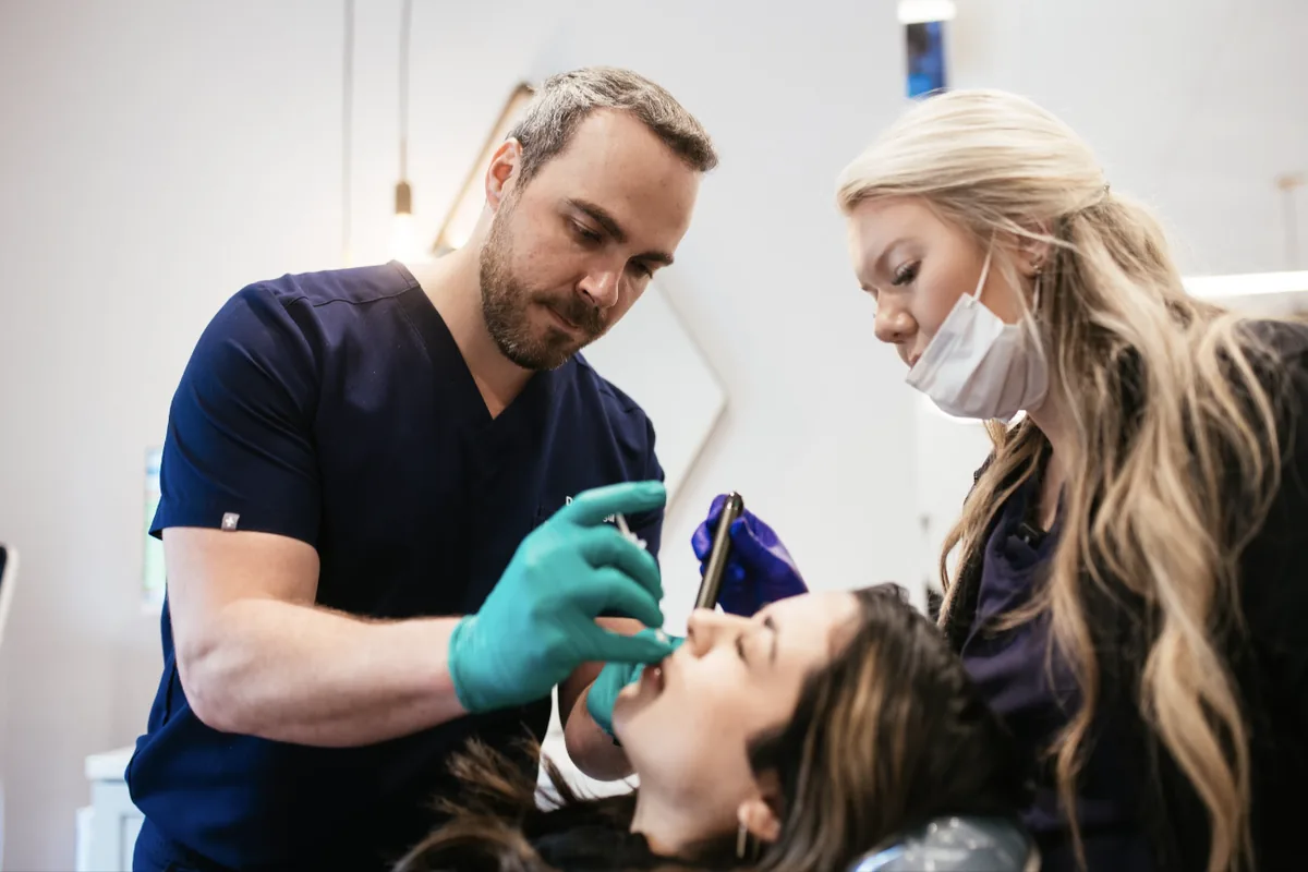 Orthodontist and assistant checking an adult patient's teeth during an orthodontic appointment